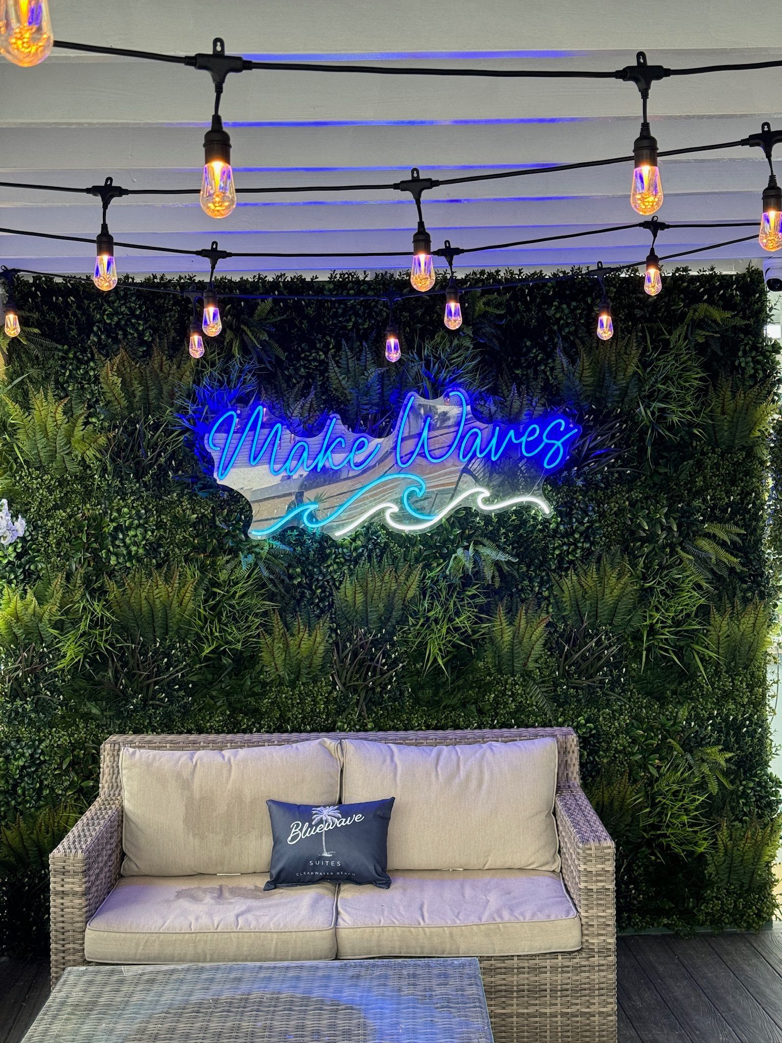 A couch is sitting in front of a green wall with a neon sign on it.
