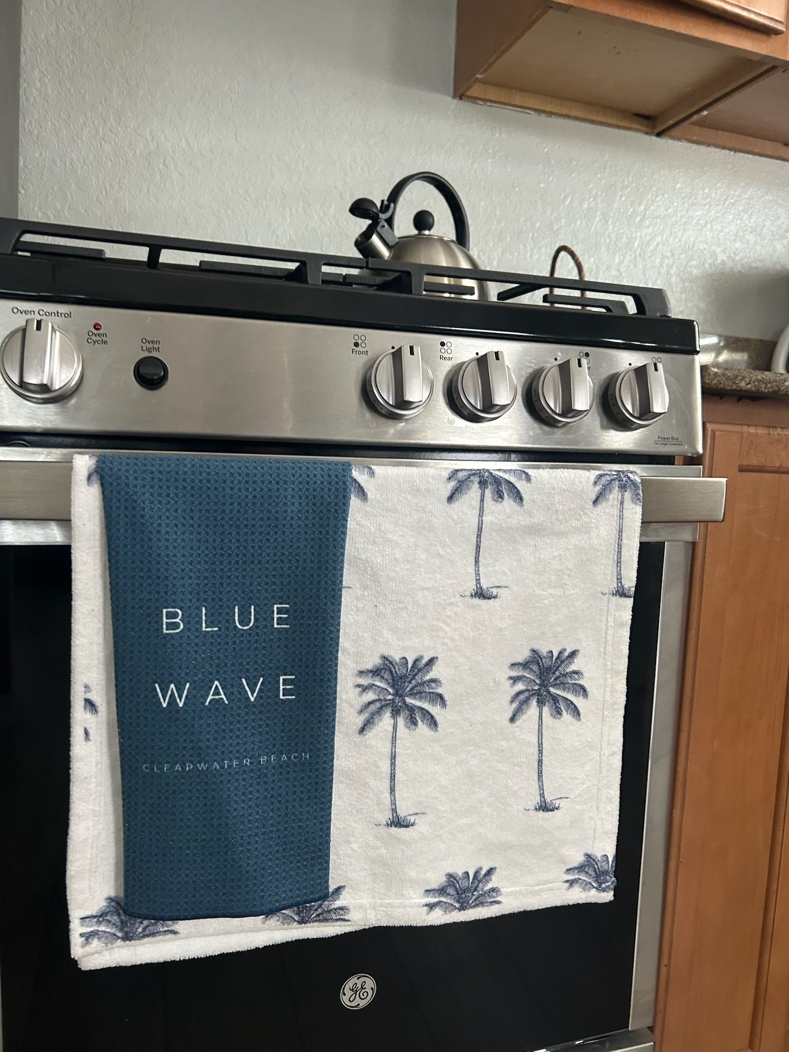 A stove top oven with a towel on it that says blue wave