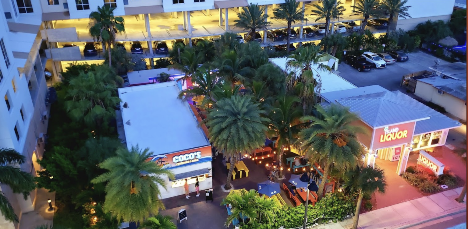 An aerial view of a restaurant with palm trees in front of it.