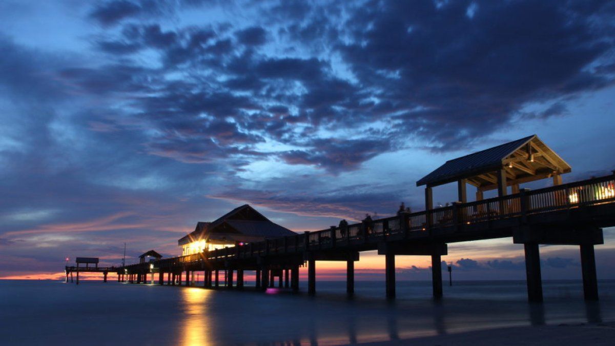 A pier with a sunset in the background and people walking on it