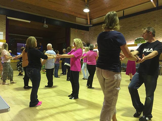 A man wearing a fila shirt is dancing with a group of people