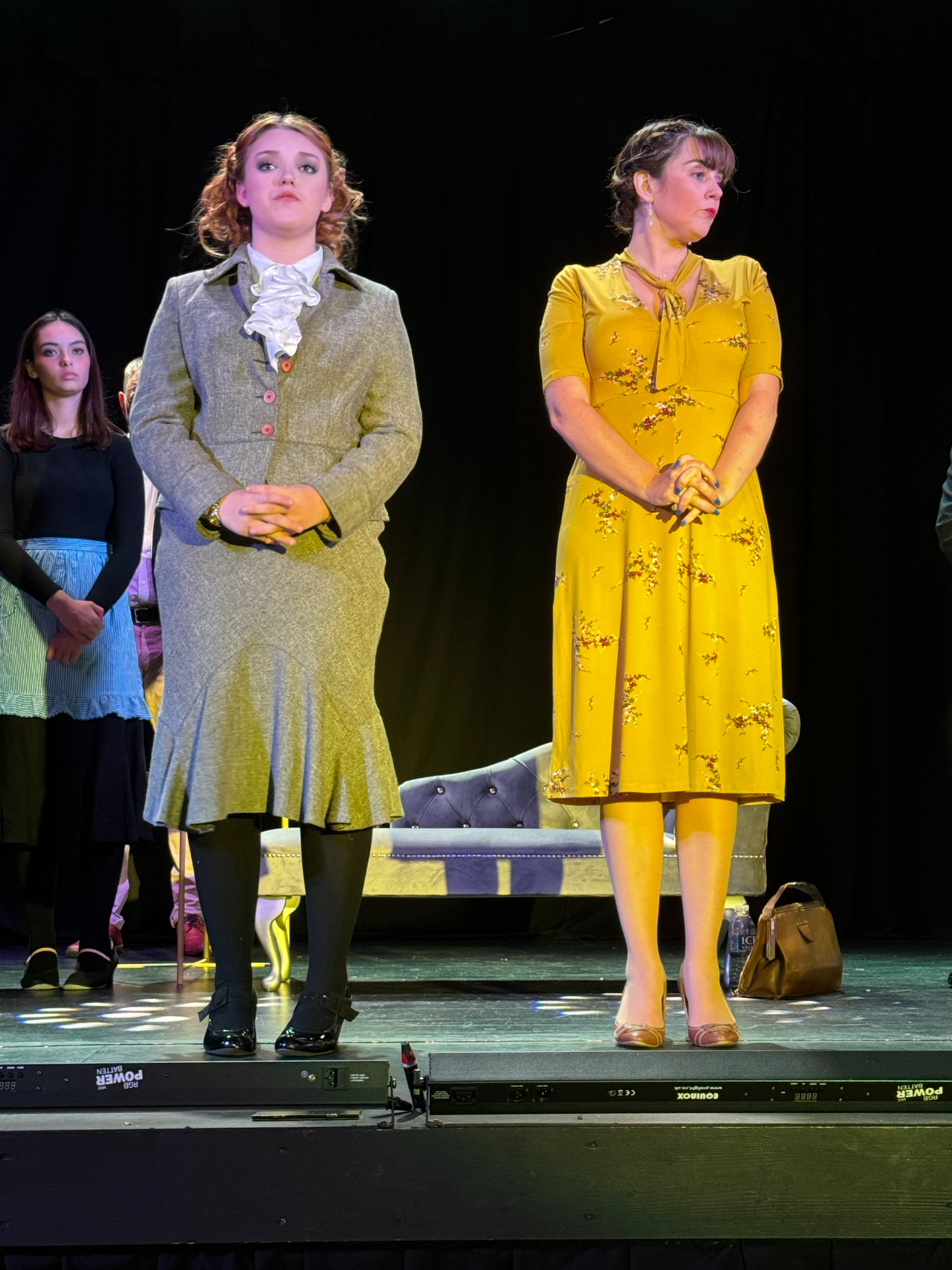 Two women in yellow dresses are standing next to each other on a stage.