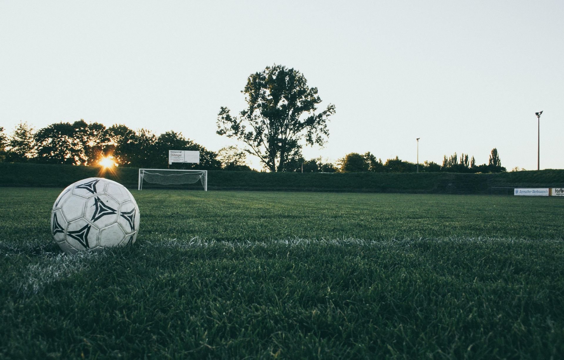 A soccer ball is sitting on the edge of a soccer field.