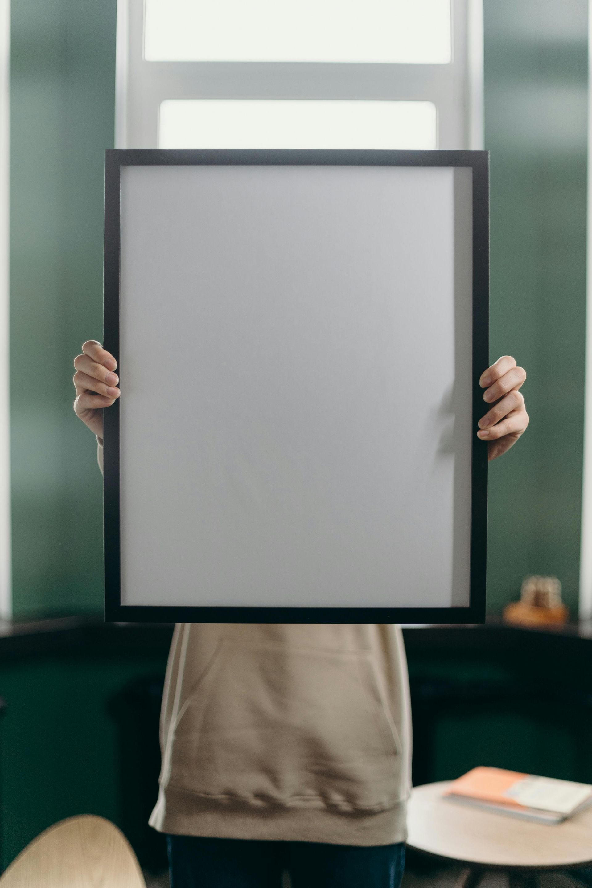 A person is holding a picture frame in front of their face.