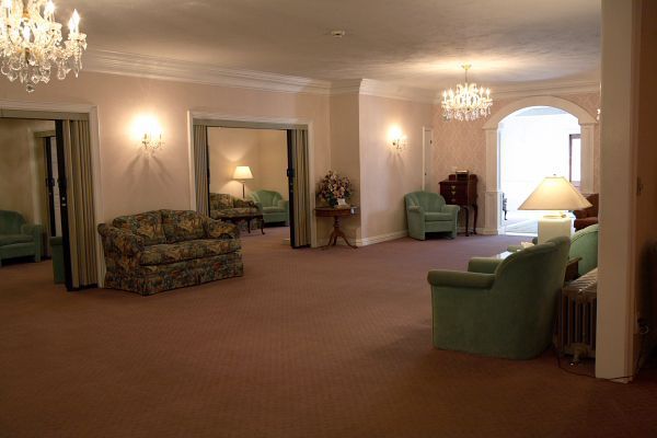 A living room with a couch , chairs , lamps and a chandelier.