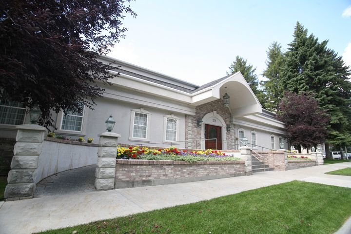 A large white building with a red door and flowers in front of it