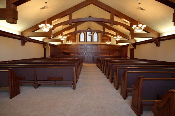 A white building with a gray roof is surrounded by trees