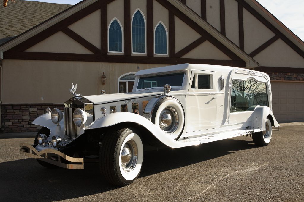 A white limousine is parked in front of a house