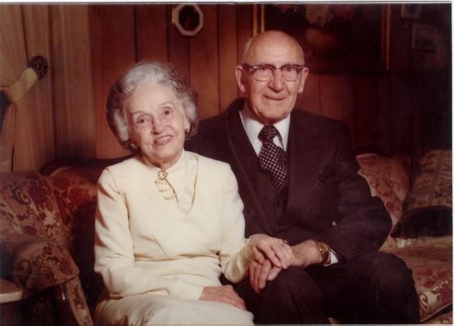 A man and woman are sitting on a couch holding hands