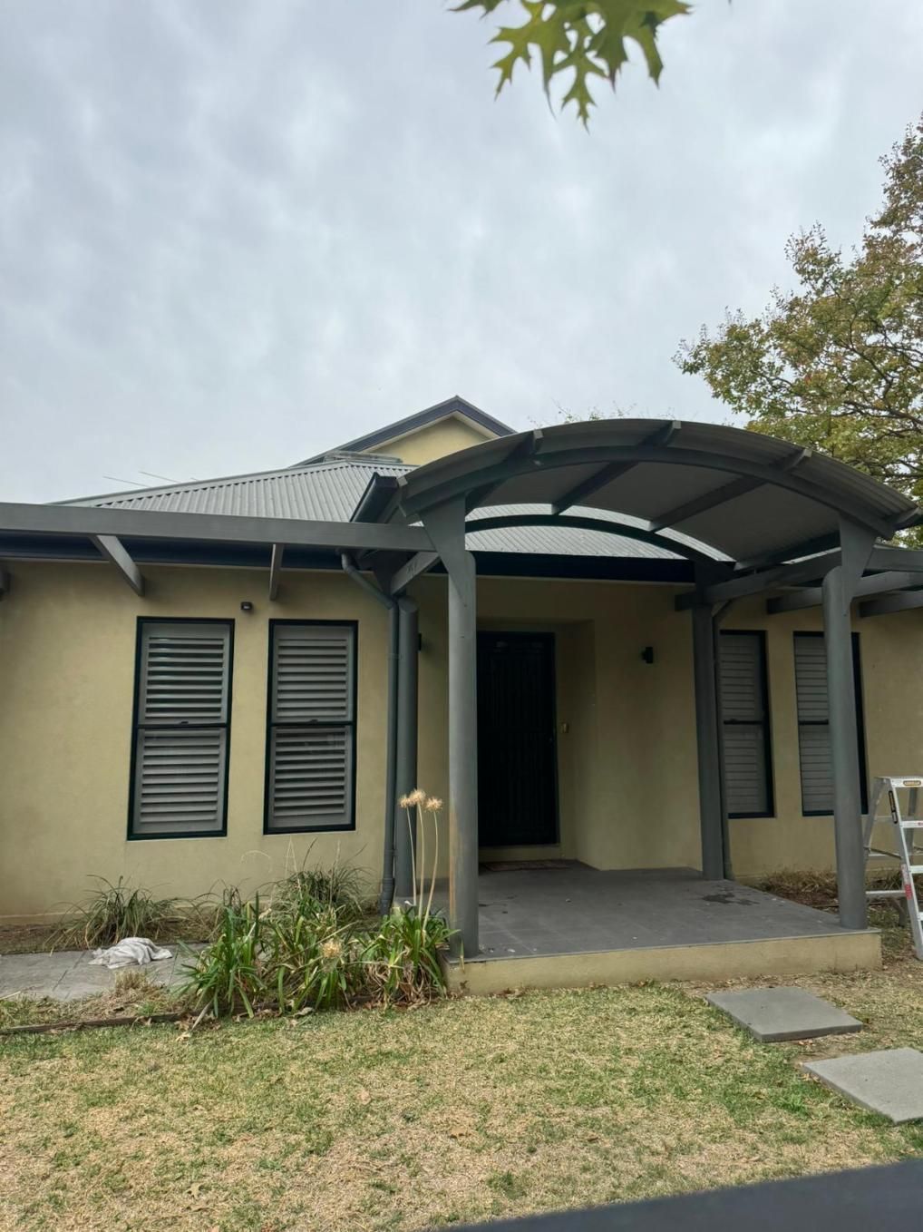 Beige House With a Carport and Closed Grey Shutters, in a Yard — Andrew Harper Painting & Decorating in Albury, NSW