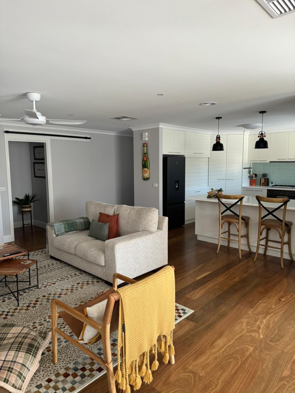 Open-concept living space with a sofa, kitchen, and wooden floors — Andrew Harper Painting & Decorating in Albury, NSW