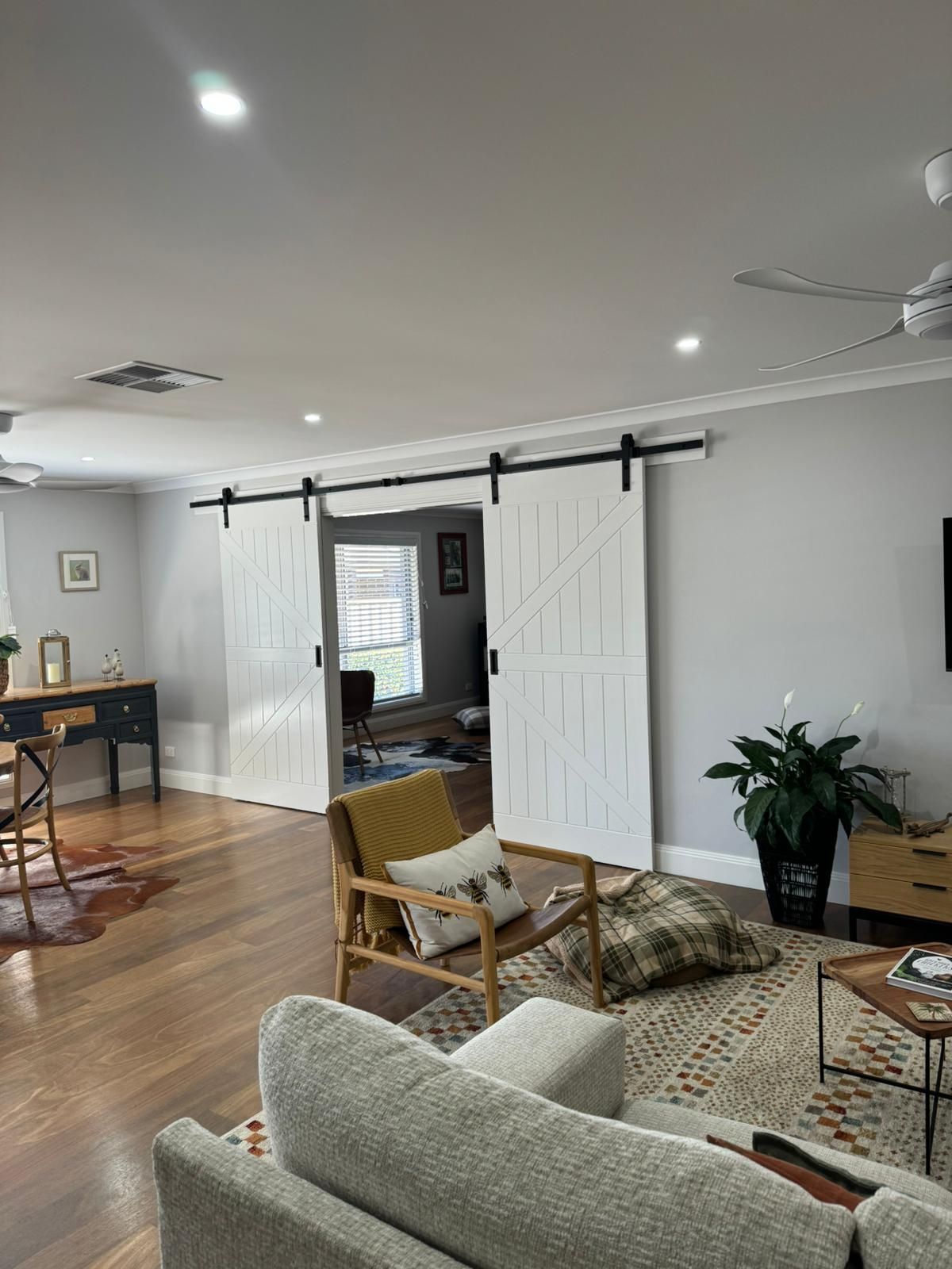 Living room with white barn doors, wood floors, and neutral furniture — Andrew Harper Painting & Decorating in Albury, NSW