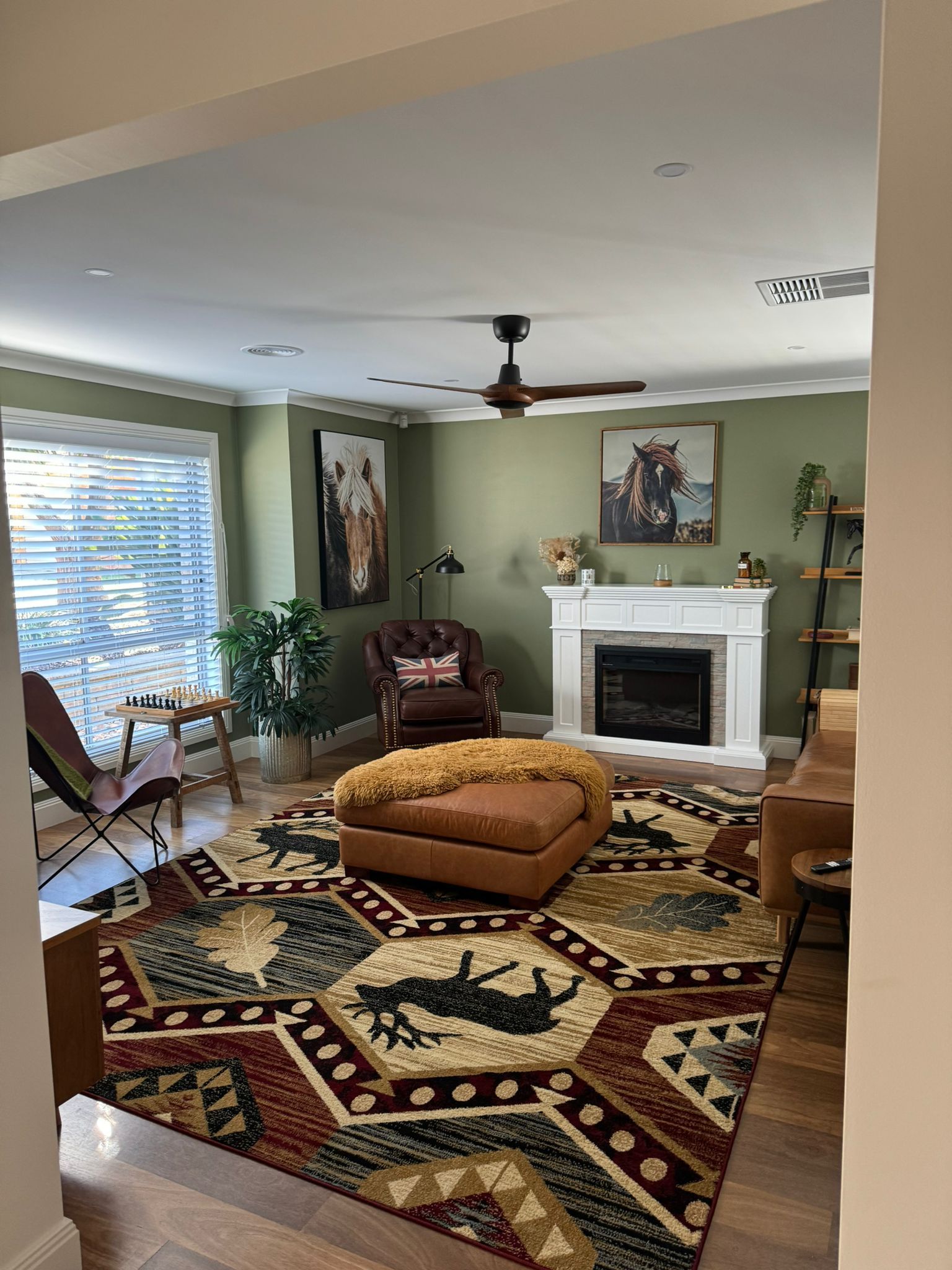 Living room with olive green walls, fireplace, patterned rug, ottoman, and artwork — Andrew Harper Painting & Decorating in Albury, NSW