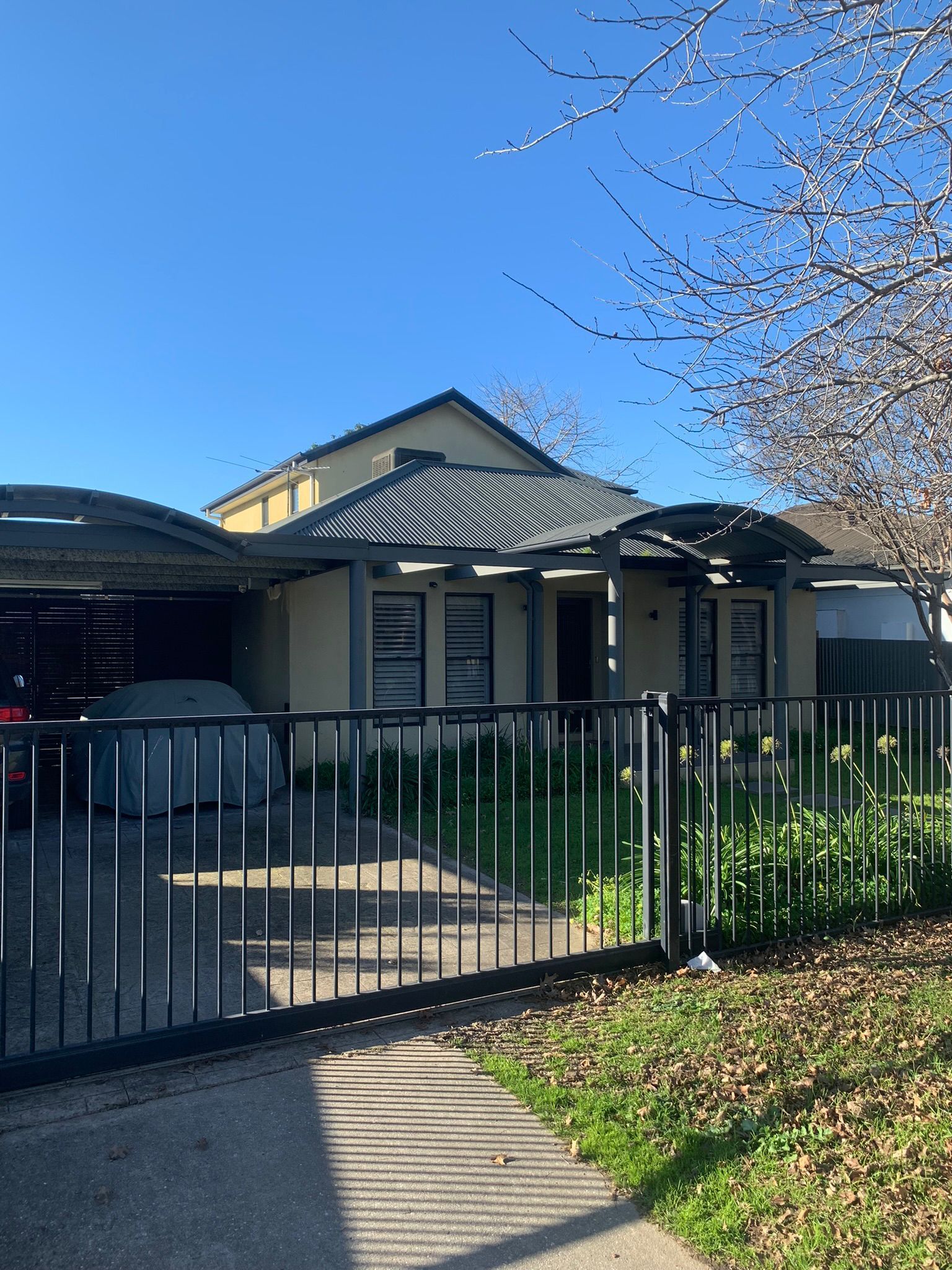House with carport and black metal gate. Green grass and blue sky — Andrew Harper Painting & Decorating in Albury, NSW