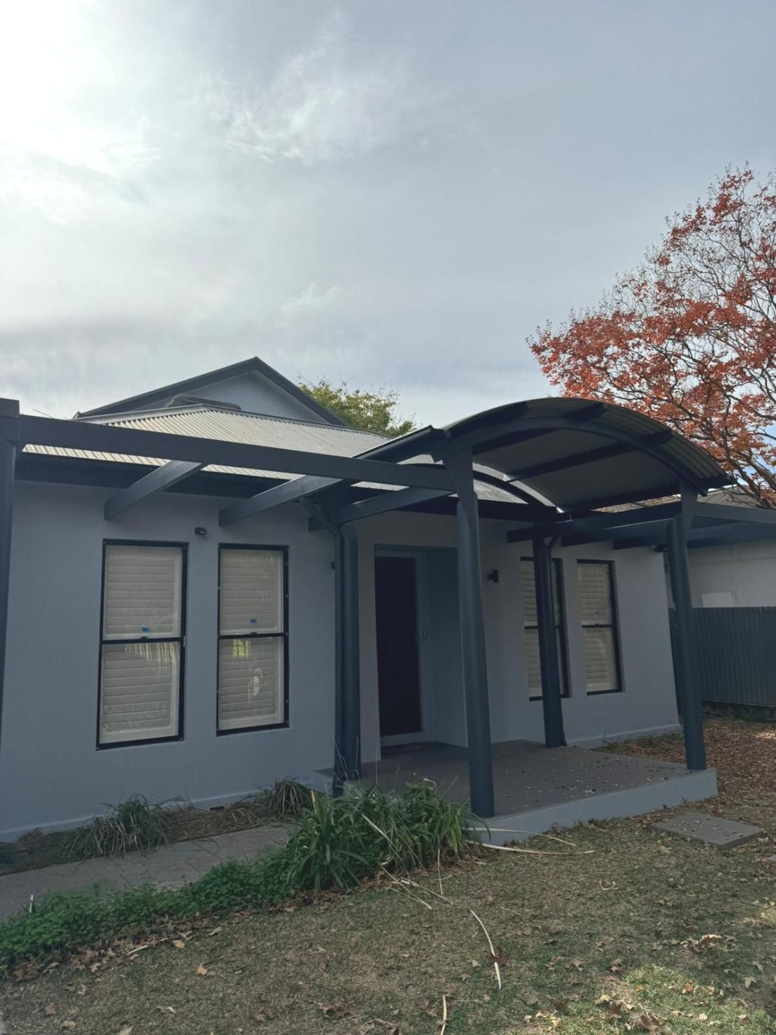 Grey House With Awning and Red-orange Tree in the Background — Andrew Harper Painting & Decorating in Albury, NSW
