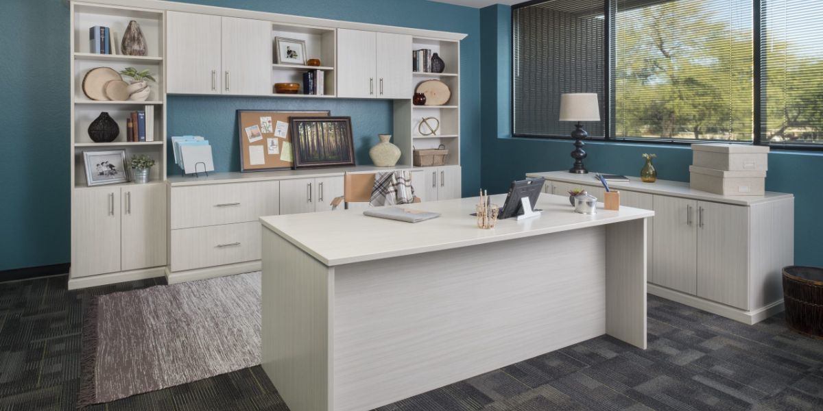 There is a large desk in the middle of the home office room.