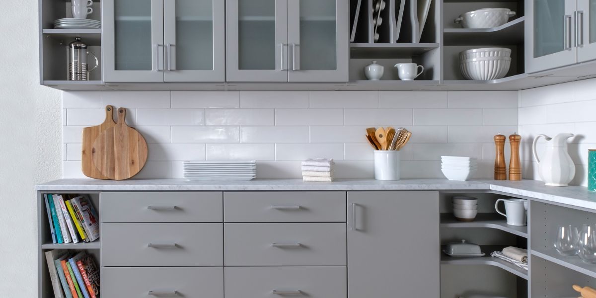 A kitchen pantry with gray cabinets and white counter tops.