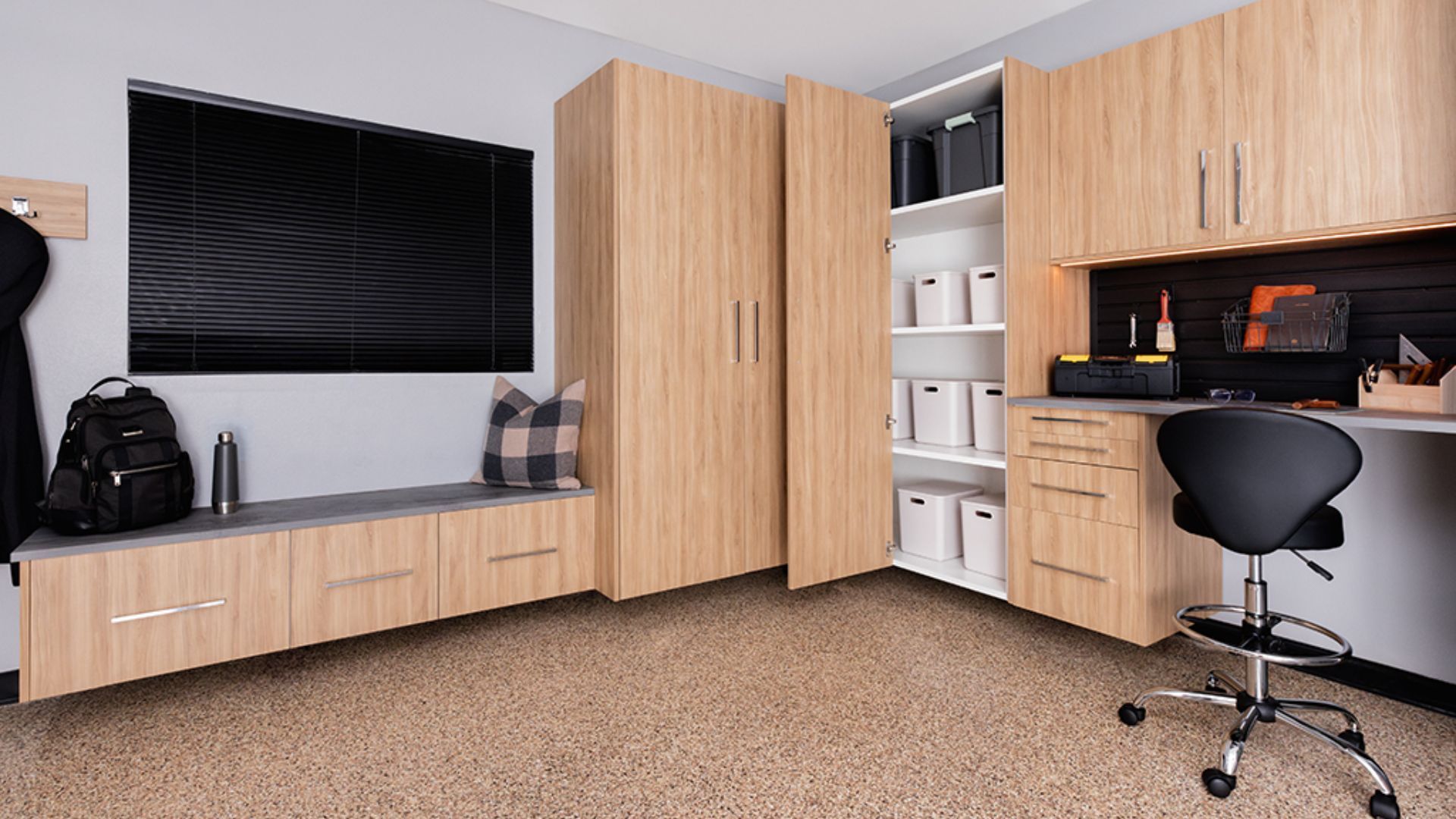 A room with wooden cabinets , a desk , a chair and a television.