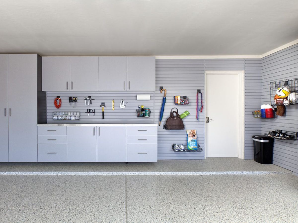 A garage with white cabinets , drawers , and a sink.