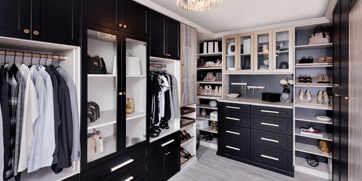 A black finish walk in closet filled with lots of clothes, bags ands shoes.