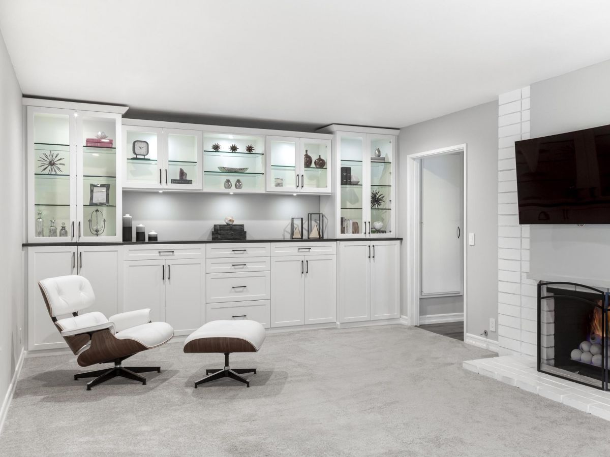 An Entertainment  living room with a chair , ottoman , television and fireplace.