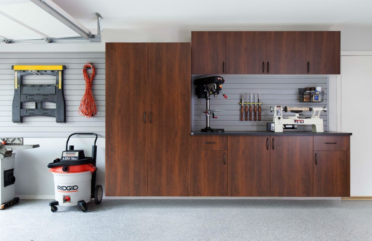 A garage with lots of cabinets and a vacuum cleaner.