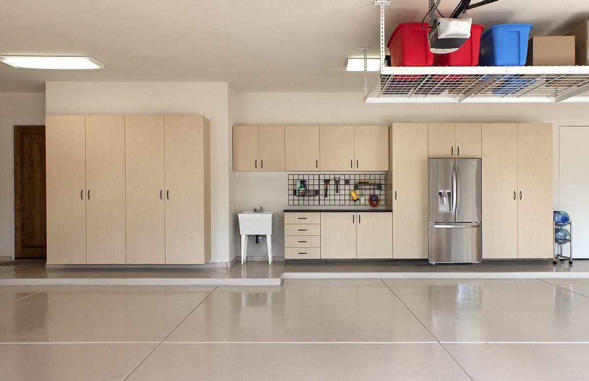 An empty garage with stainless steel appliances and wooden cabinets.