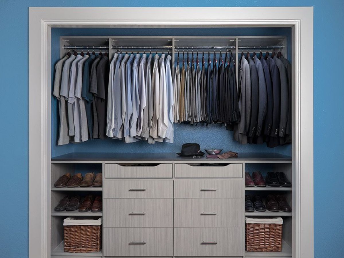 A white reach closet filled with lots of hanged clothes and shoes.
