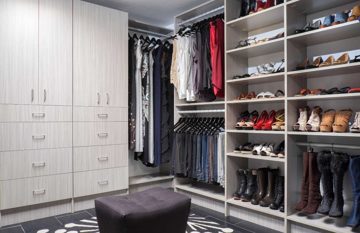 A walk in closet filled with lots of clothes and shoes.