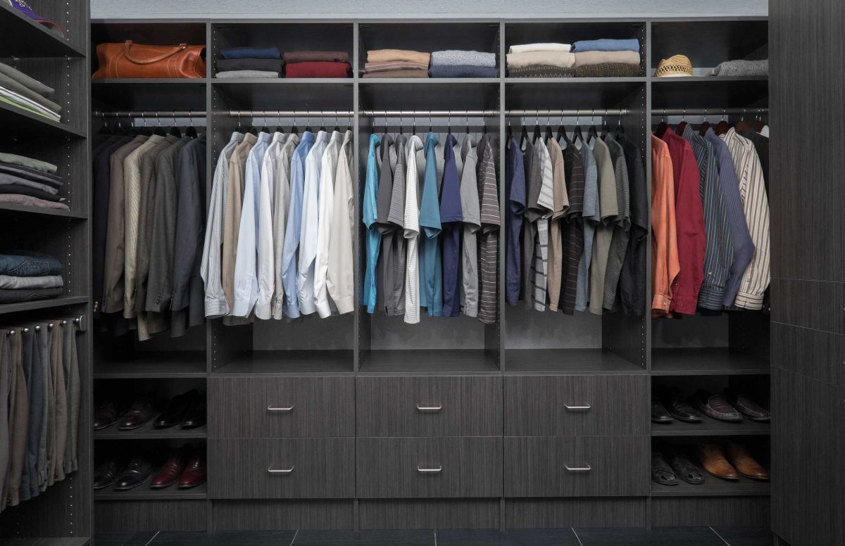 A walk in closet filled with lots of clothes and shoes.