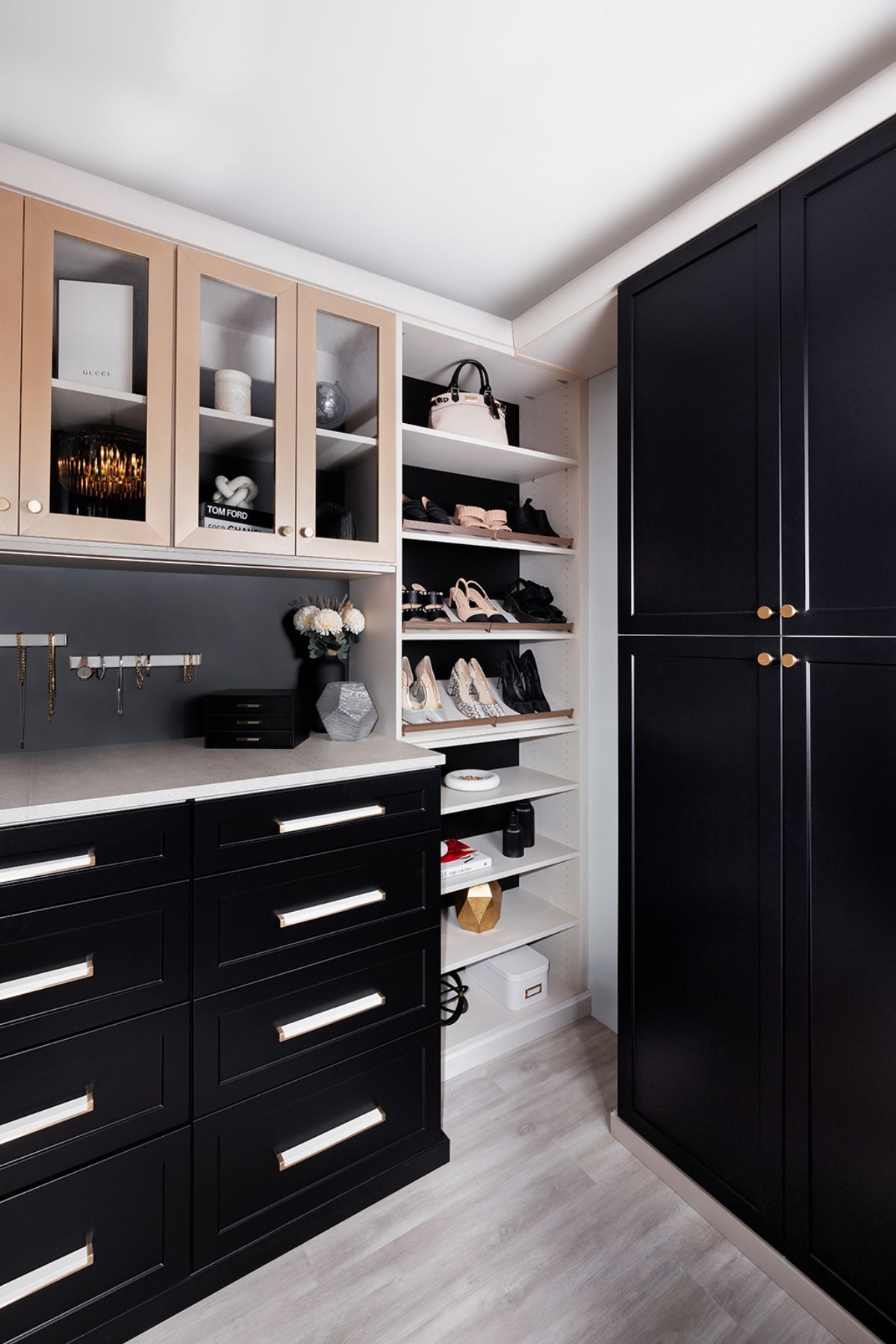 A walk in closet with black cabinets and shelves