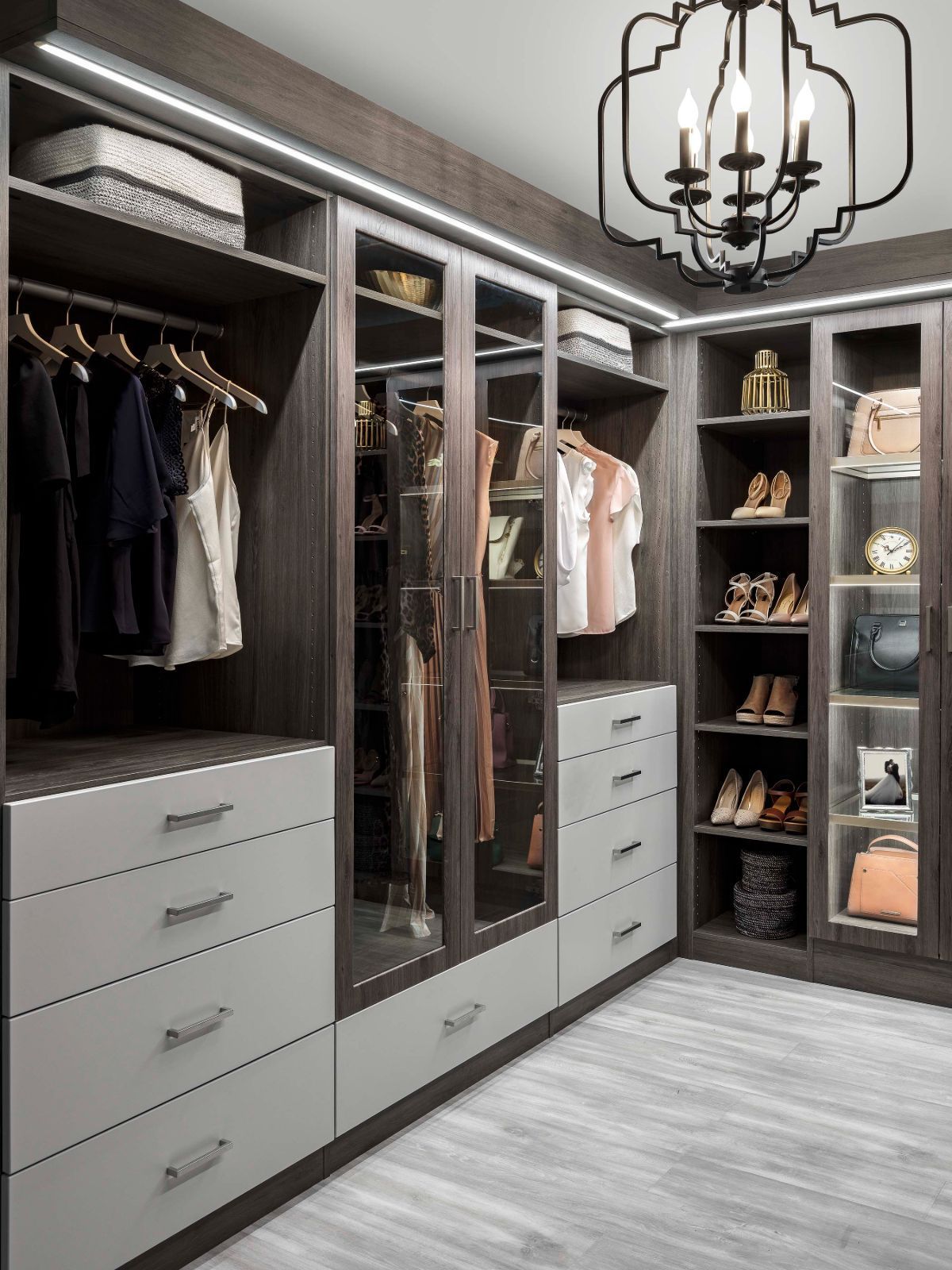 A walk in closet with lots of clothes and a chandelier.