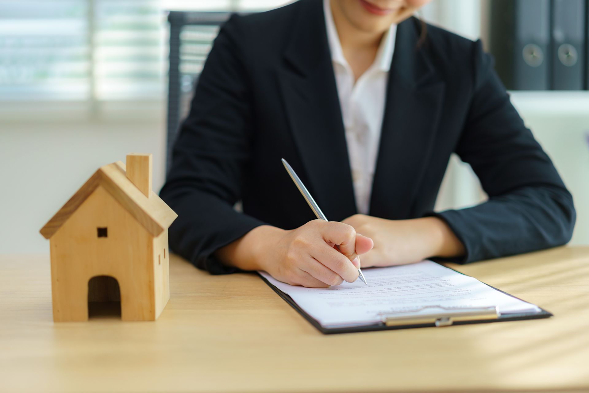 A woman signing a contract, showcasing her role as a local real estate attorney.