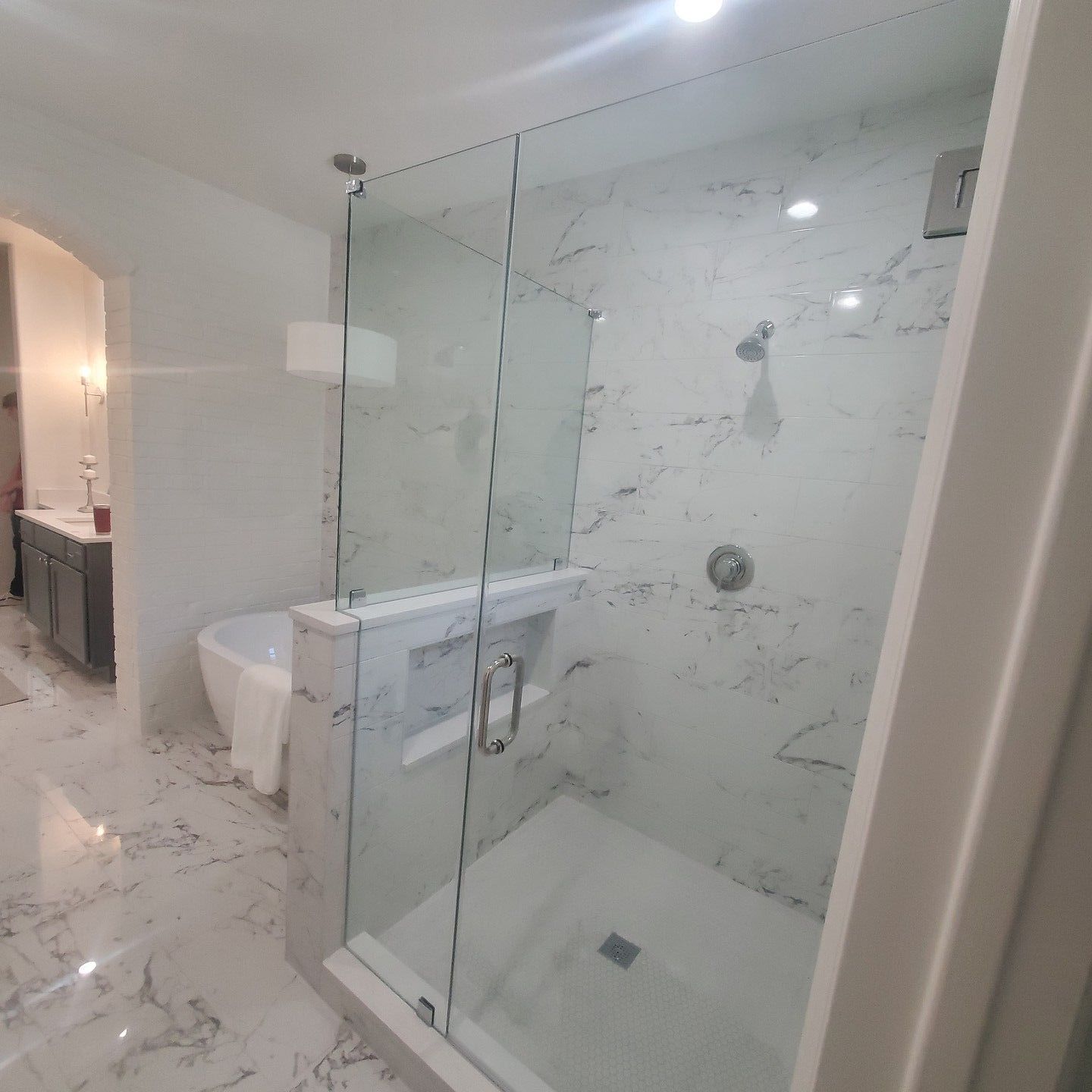 Modern bathroom with marble tile and a frameless glass shower enclosure.