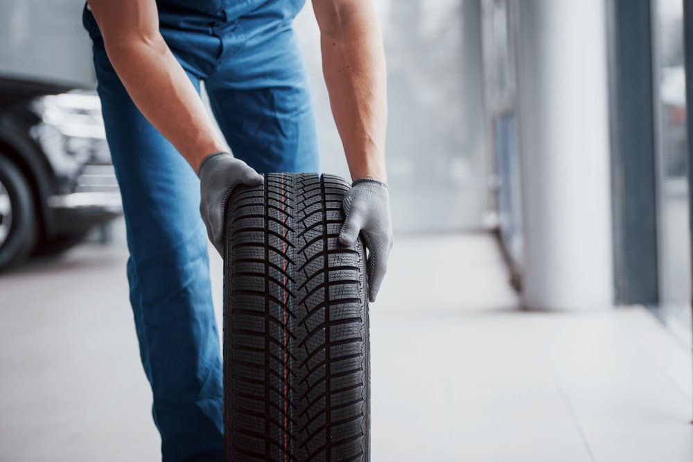 Mechanic Rolling a Tyre — Batteries & Tyres in Wellington, NSW