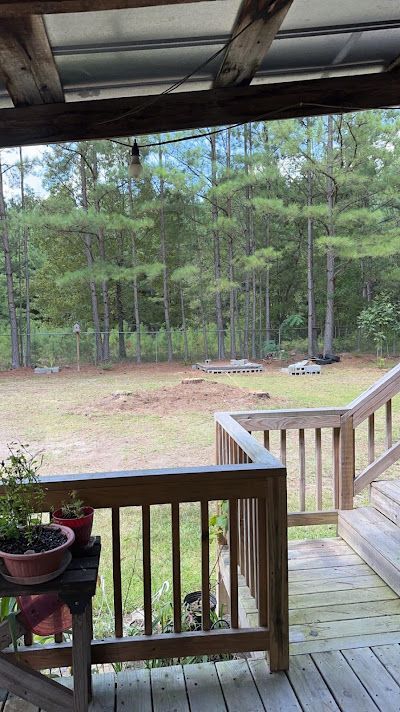 A wooden deck with a view of a field and trees.