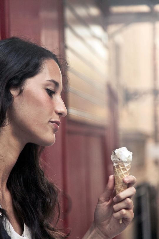 A woman is holding an ice cream cone in her hand.