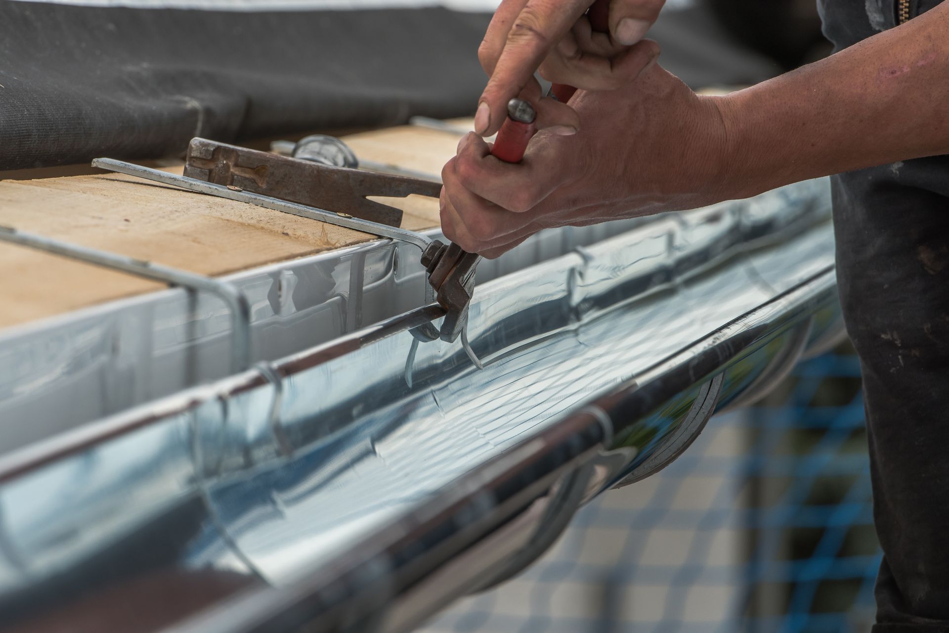 Hands adjusting metal hardware on a rooftop gutter or track system Hands adjusting metal hardware on a rooftop gutter or track system
