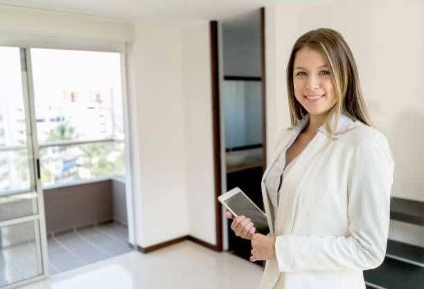A woman in a white suit holds a tablet, representing vacation rental management in Honolulu, HI, by Hawaiian Properties.