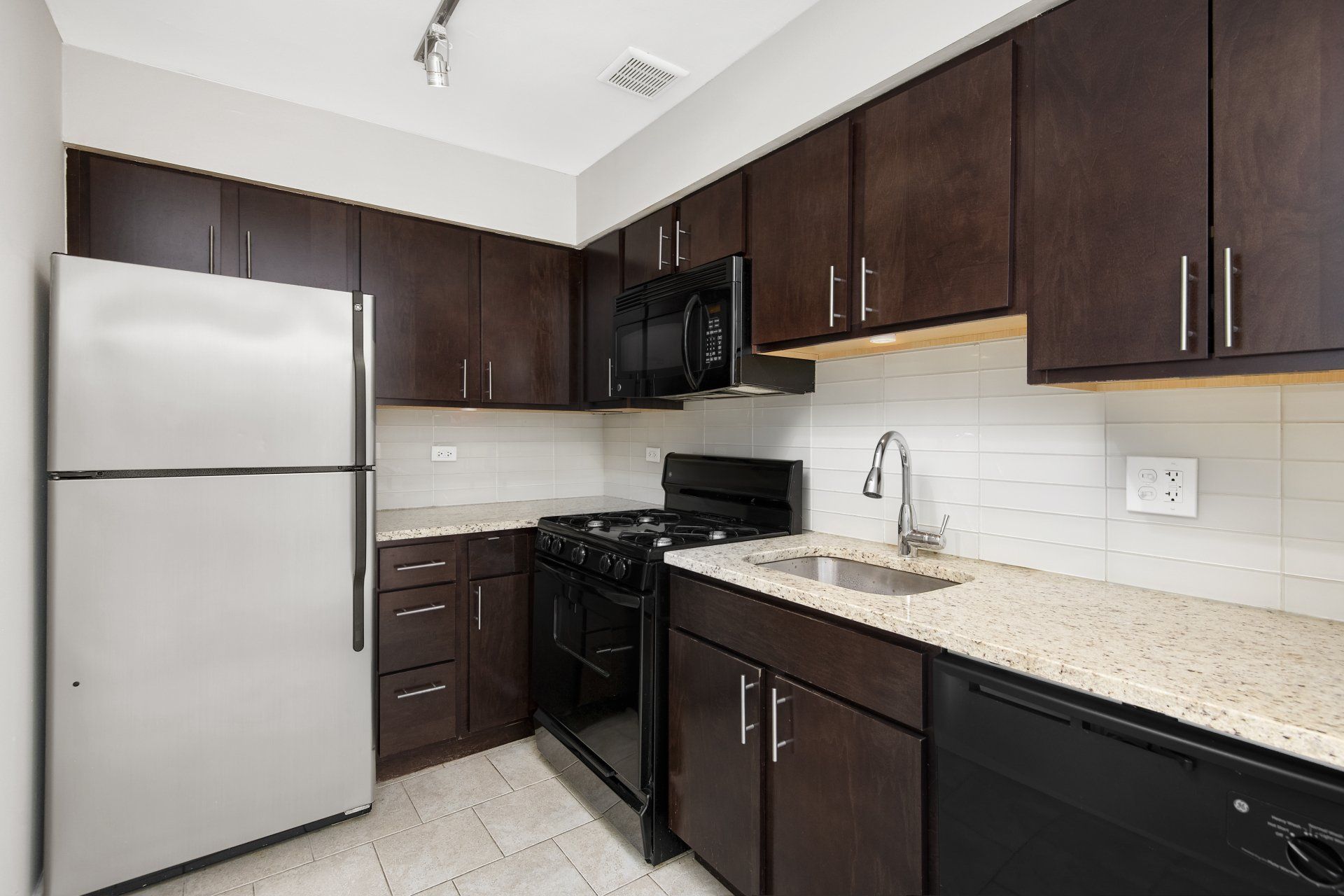 A kitchen with a refrigerator, stove, sink, and dishwasher at Reside on Pine Grove.