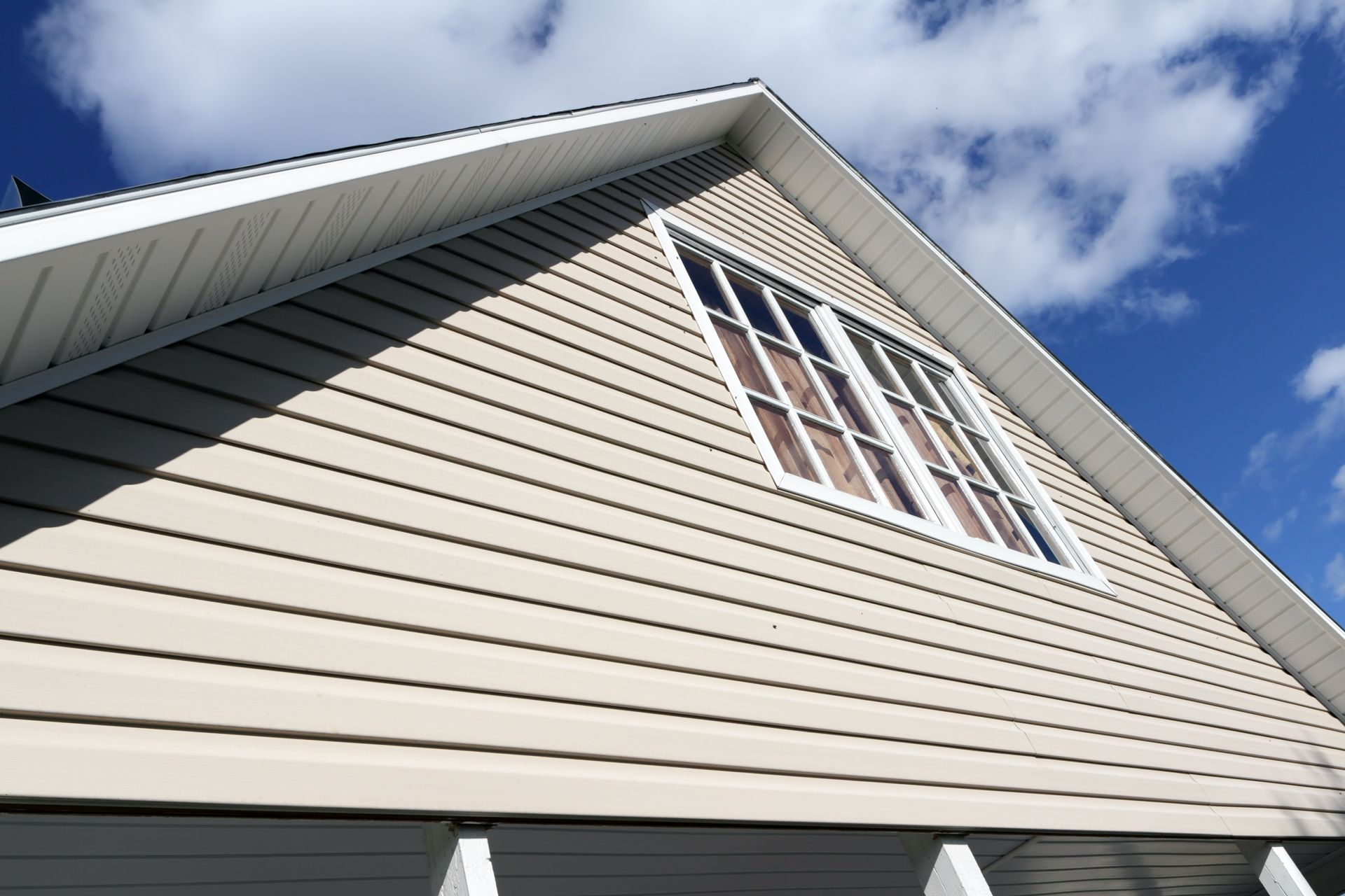 Looking up at the roof of a house with a blue sky in the background