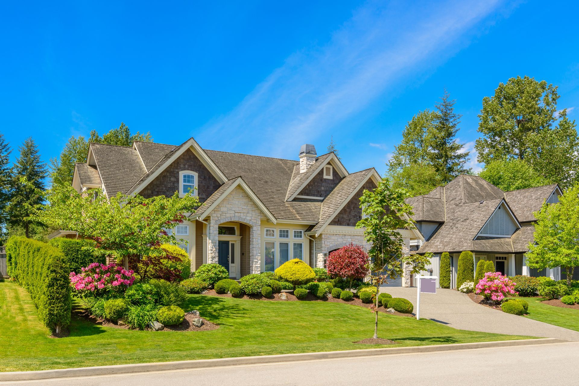 A large house is sitting on top of a lush green lawn in a residential neighborhood.