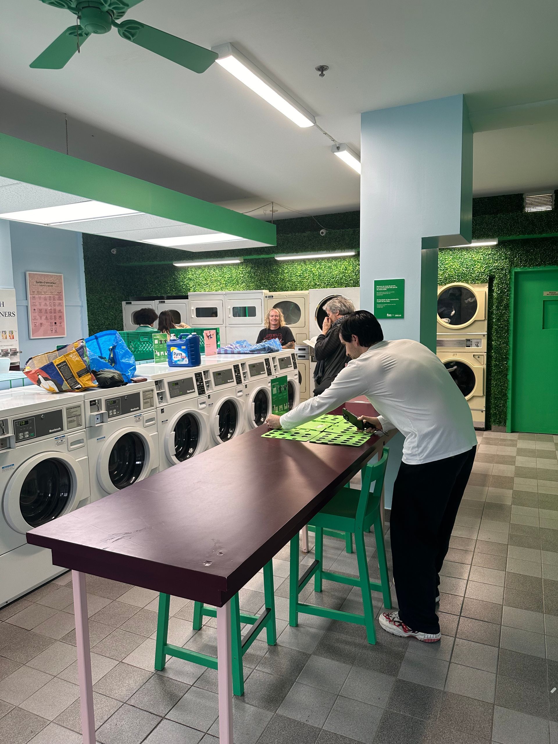 A man is standing at a table in a laundromat.