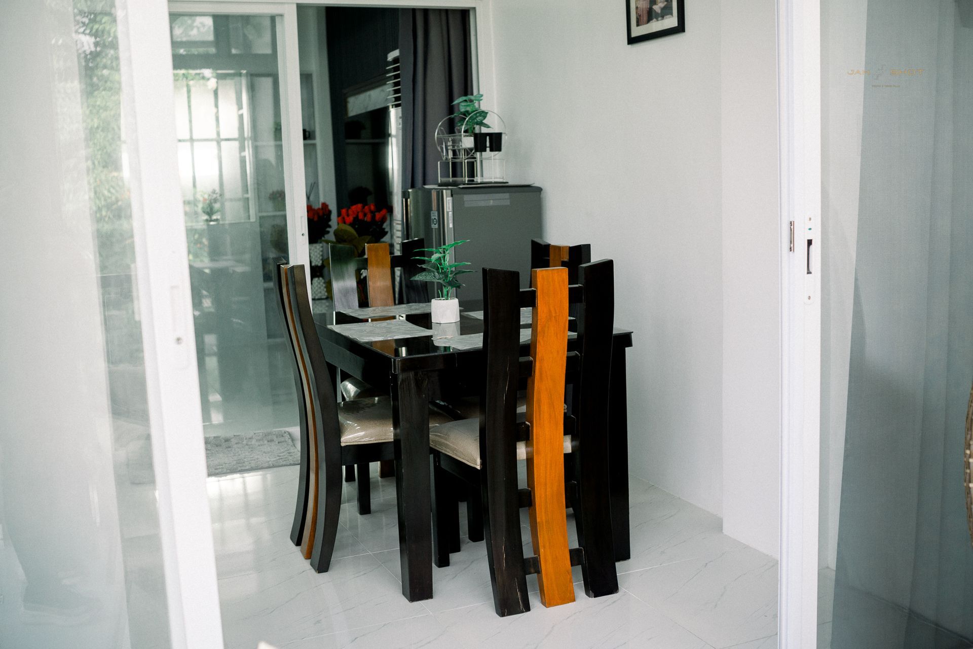 A dining set with a dark wooden table and chairs with central light-wood accents in a bright, modern room.