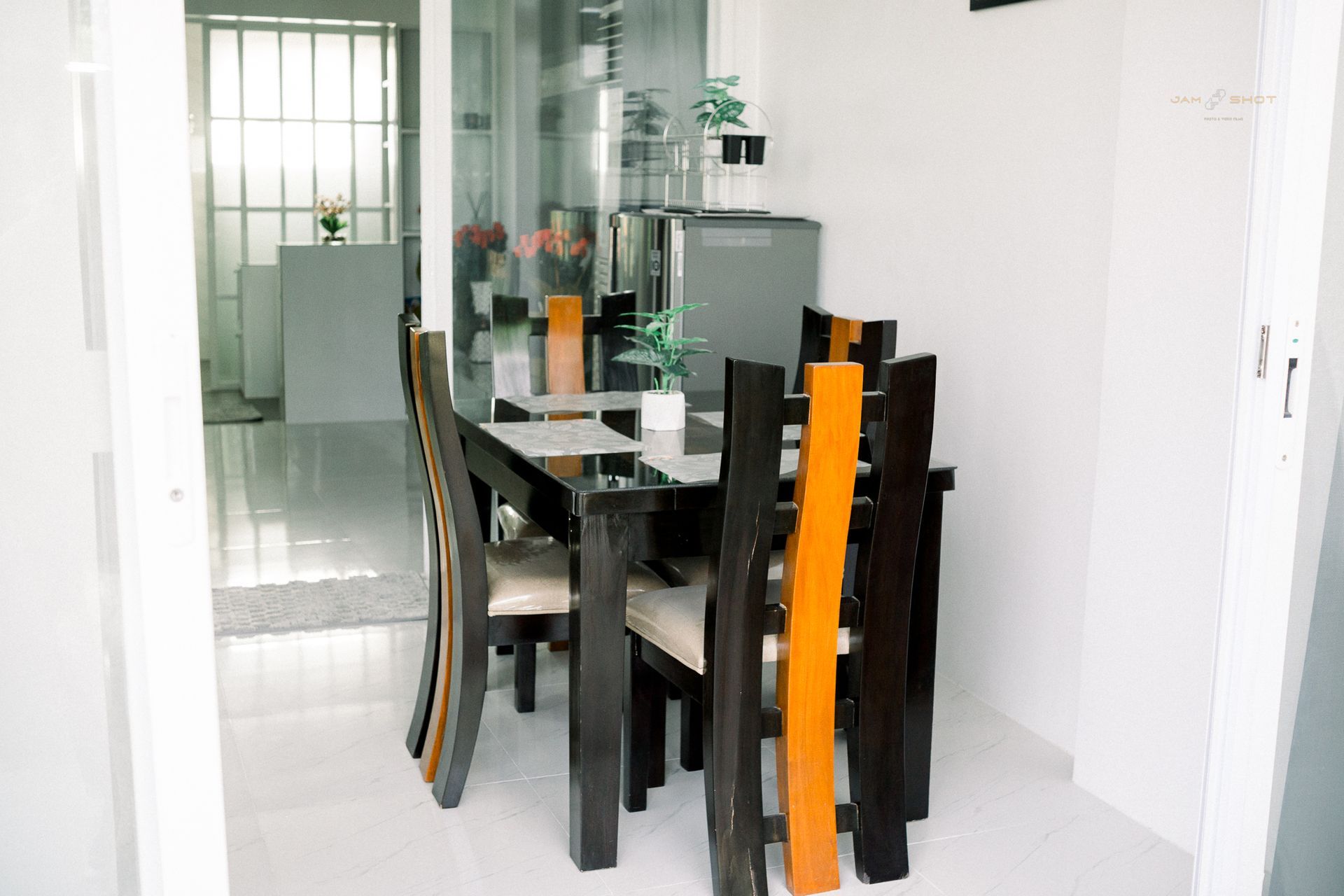 A dining set with a dark wooden table and four chairs featuring unique, tall orange-toned center slats in a bright room.