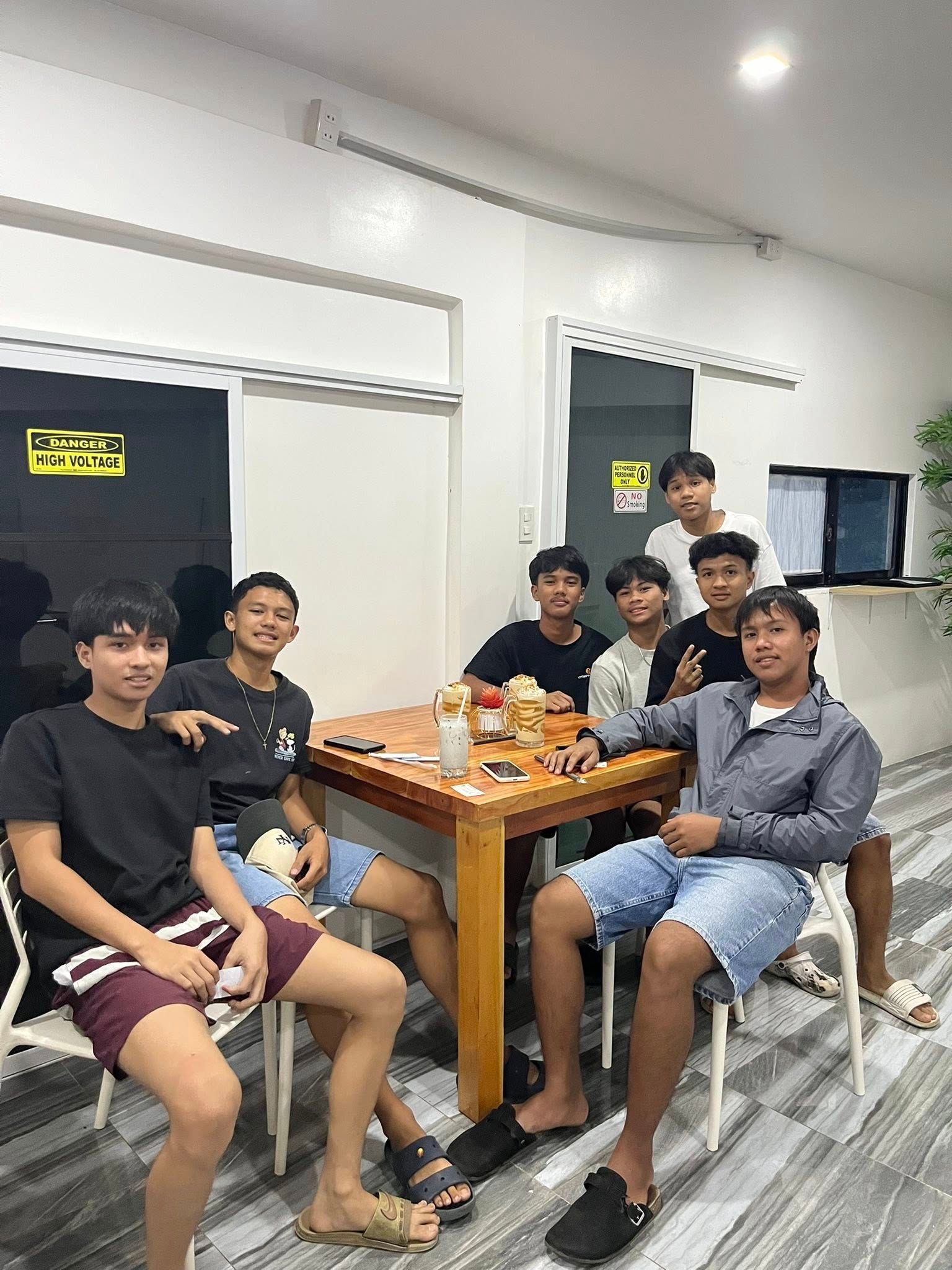 A group of seven people sitting at a wooden table in a bright, modern room, smiling for a photo.