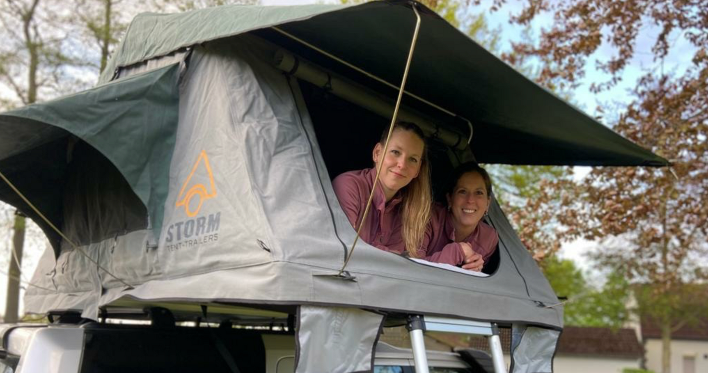 Evelien en Marlies  zitten in een STORM daktent bovenop een auto.