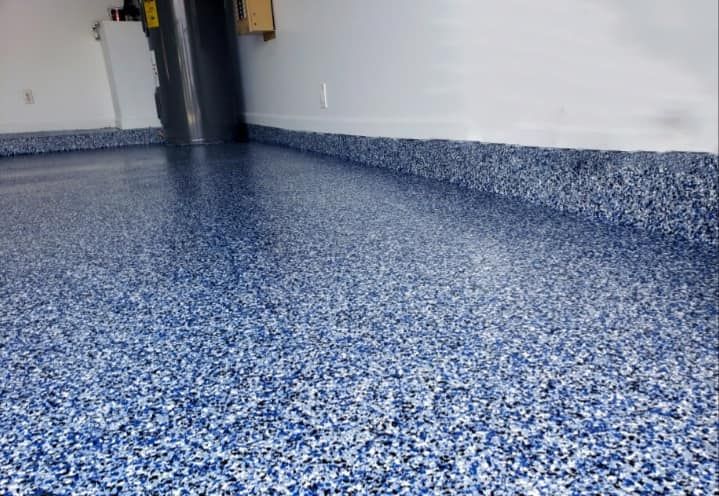 A blue and white floor in a garage with a white wall
