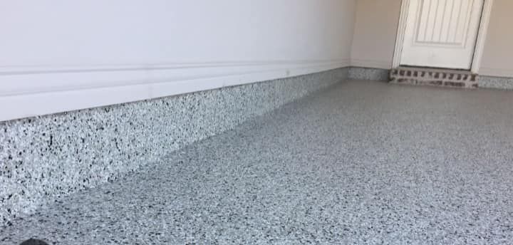 A close up of a garage floor with a door in the background.