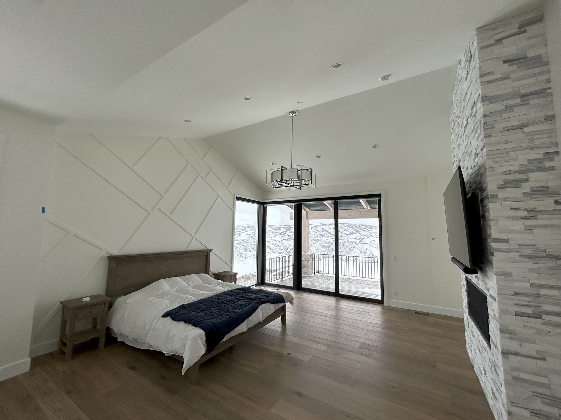 A bedroom with a bed , nightstand , television and sliding glass doors.